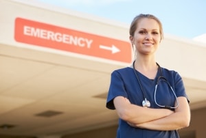 Young nurse standing in front of a sign that says EMERGENCY